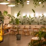 Elegant café interior with plants and warm lighting, creating a cozy ambiance.