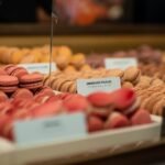 Vibrant macarons on display in a Paris market bakery, showcasing a variety of flavors.